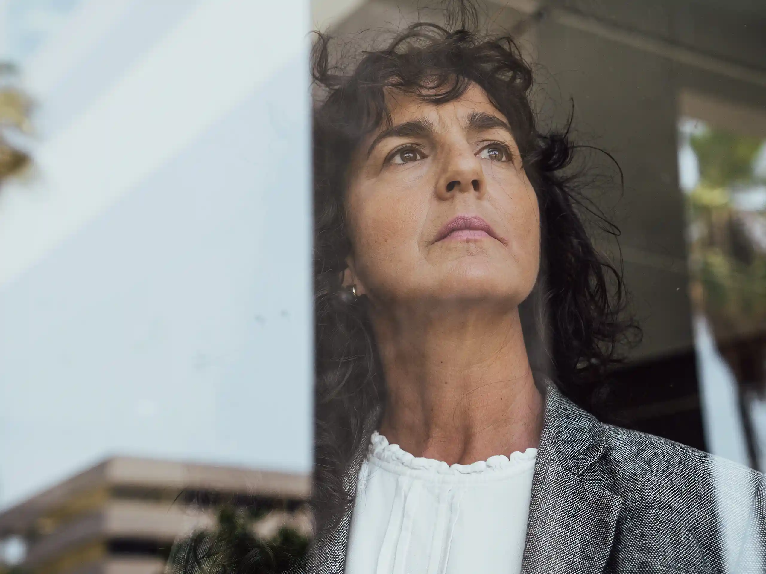 Frau blickt nachdenklich aus einem Fenster nach draußen.