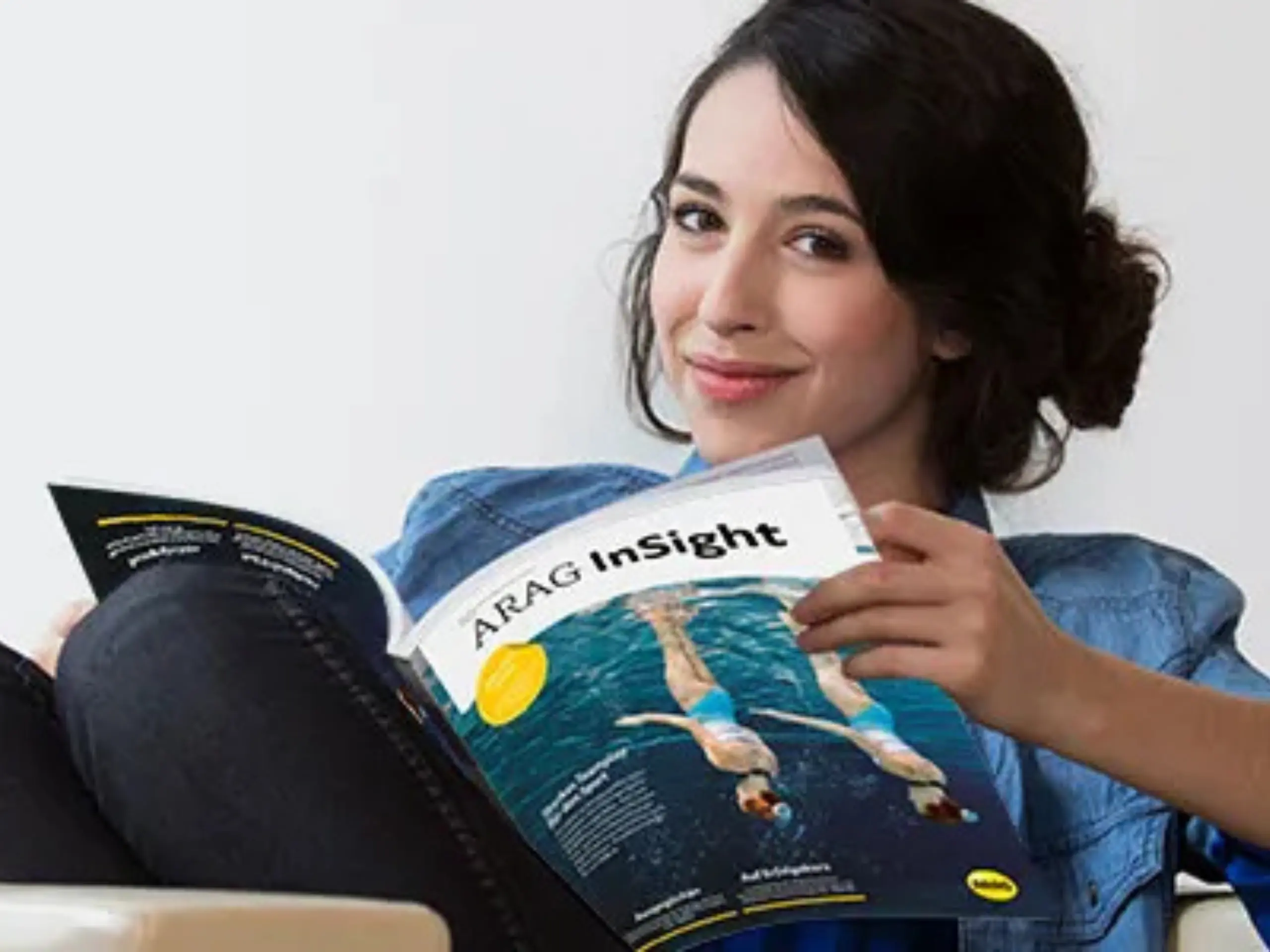 Frau hält ARAG Magazin in der Hand und schaut in Kamera