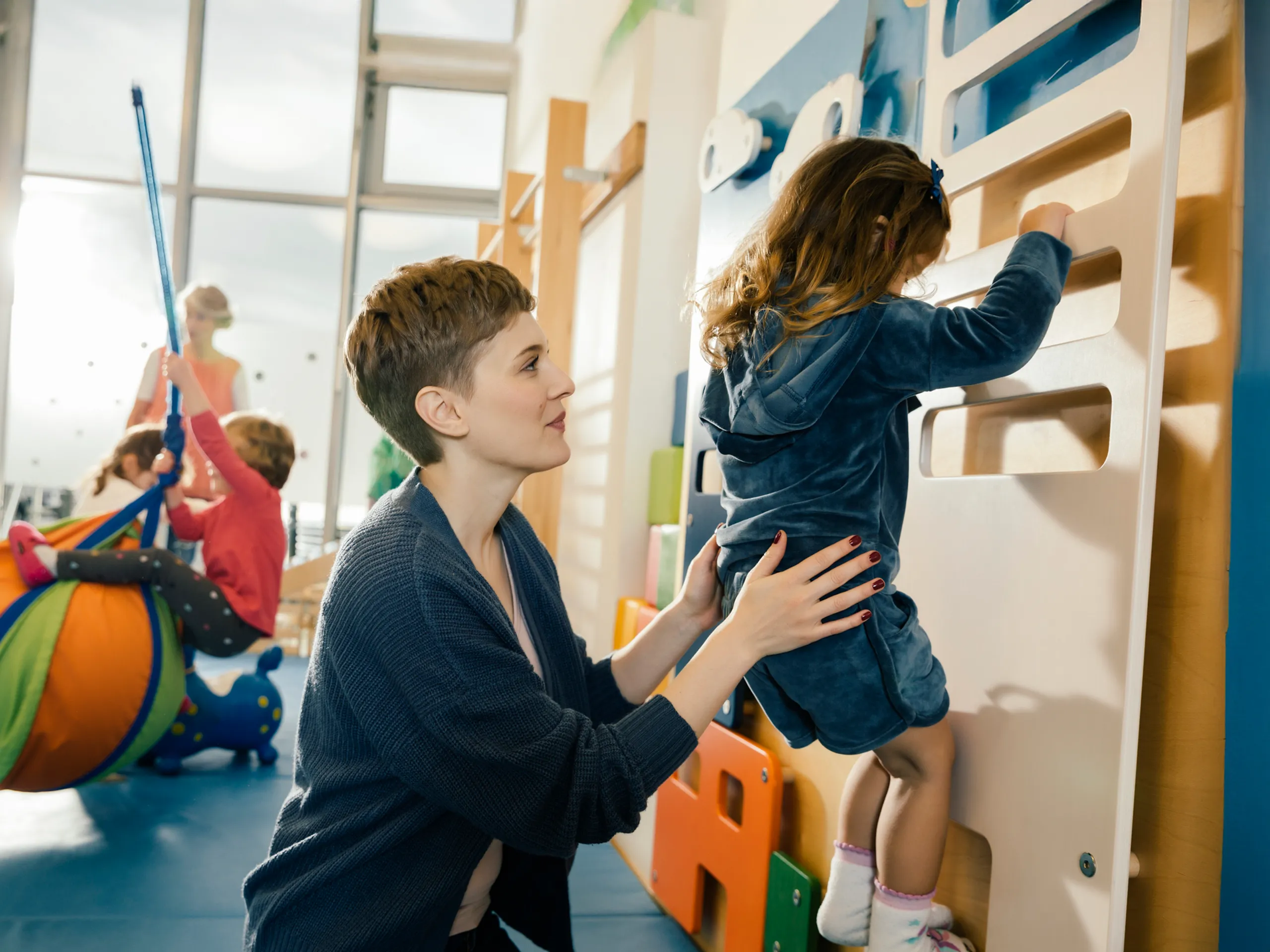 Frau hält Kind an Kletterwand